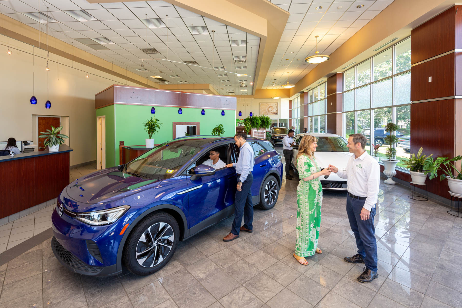 Люди возле автомобилей в просторном салоне Green Wave EV.